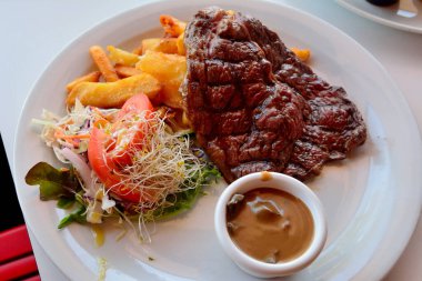 Salata, kızarmış patates ve mantar soslu biftek tabağı..