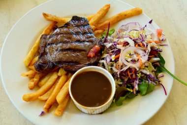 Salata, kızarmış patates ve mantar soslu biftek tabağı..