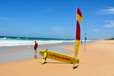 Noosa, Queensland, Avustralya - 20 Aralık 2017. Noosa, QLD 'nin güneyindeki Sunshine Sahili' nde kırmızı-sarı bayrak ve kurtarma tahtasının yanında sörf cankurtaranı..