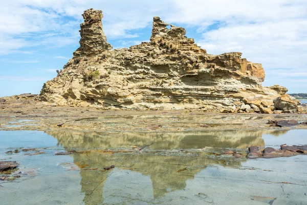 Eagles Nest rock formation in Bunurong Marine and Coastal Park in Victoria, Australia, reflecting in rock pool waters.