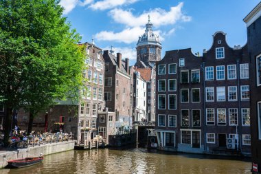 Amsterdam, Hollanda - 22 Haziran 2016. Amsterdam 'ın merkezinde De Wallen' daki Oudezijds Voorburgwal Kanalı ve caddesi manzarası. Aziz Niklas Bazilikası 'na doğru bakın..