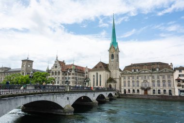 Zürih, İsviçre - 25 Haziran 2016. Zürih 'teki Munsterbrucke Köprüsü ve Fraumunster Kilisesi manzarası, çevresindeki tarihi binalar ve insanlar.