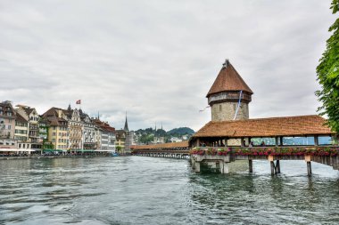 Lucerne, İsviçre - 26 Haziran 2016. Kapellbrucke 'nin Lucerne' deki Reuss Nehri 'ni kaplayan tahta köprü manzarası. Köprü 1333 yılından kalma. Wasserturm su kulesi, tarihi binalar ve insanlar ile manzara.