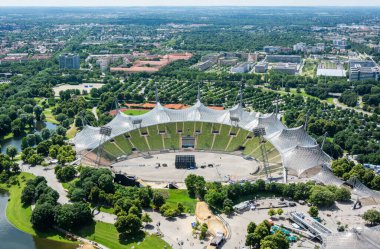 Münih, Almanya - 1 Temmuz 2016 Yaz aylarında Münih 'teki Olympiastadion Stadyumu ve Olympiapark' a binalar ve bitki örtüsüyle bakın. Münih 'in kuzeyinde Olympiapark Münih' in göbeğinde yer alan stadyum, Münih 'in ana merkezi olarak inşa edilmiştir.
