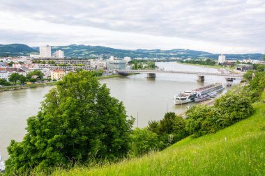 Linz, Avusturya - 25 Mayıs 2017. Linz 'deki Tuna Nehri üzerinde tekne, bitki örtüsü ve binalarla.