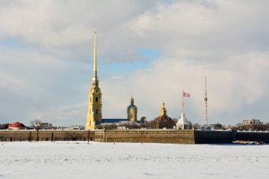 Exterior view of Peter and Paul Fortress and Cathedral in St Petersburg, Russia, across frozen Neva River.