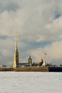 Exterior view of Peter and Paul Fortress and Cathedral in St Petersburg, Russia, across frozen Neva River.