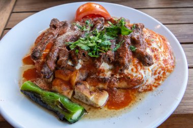 Turkish manisa kebap served on pita bread covered with sauce and yogurt.