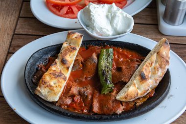 Oven baked Turkish doner with sauce, bread and fried pepper.