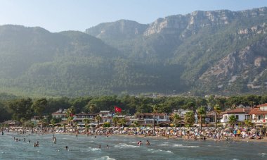 Akyaka, Mugla, Turkey - July 29, 2016. Akyaka beach in the centre of Akyaka village in Mugla province of Turkey, with Sakar mountains in the background, and people.
