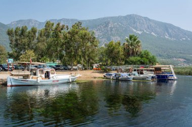 Akyaka, Mugla, Turkey - July 30, 2016. Azmak stream in Akyaka village in Mugla province of Turkey, with boats and Sakar mountains in the background.