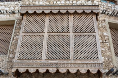 Traditional Arabic mashrabiya balcony enclosed with carved wood latticework in Doha, Qatar.