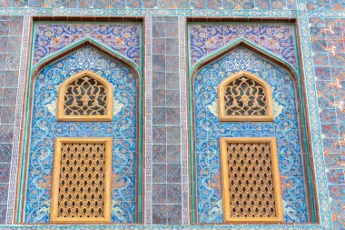 Traditional Arabic mashrabiya window on a tiled wall enclosed with carved wood latticework in Qatar.