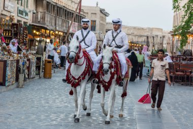 Doha, Qatar - November 3, 2016. Street view in Souq Waqif market in Doha, with two policemen riding horses, people and historic buildings.