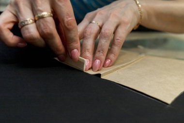 Terzi kadın, elleri atölyede kumaşla çalışıyor.