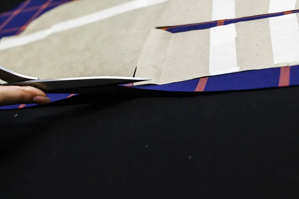 Terzi kadın, elleri atölyede kumaşla çalışıyor.