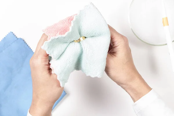 Evde altın mücevher yüzüğünü temizleyen kadın elleri. Üst görünüm