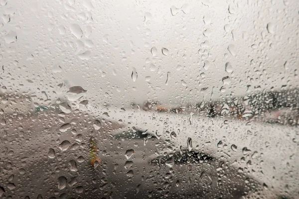 Zicht op vliegtuigvleugel door passagiersraam met regendruppels op regenachtige dag — Stockfoto