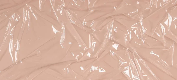 Crumpled wrinkled plastic transparent plastic cellophane on pastel brown color background. Abstract creative texture background — Stock Photo, Image