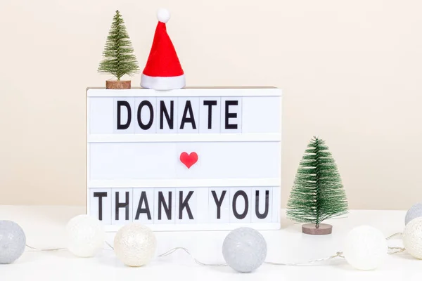 Juldonation, välgörenhet. Donera och tack meddelande på lightbox. Juldekoration och krans på vitt skrivbord. Framifrån, på nära håll — Stockfoto