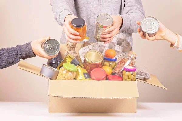 Volontärer händer samla livsmedel till mat donationer box för fattiga familj, hemlösa människor — Stockfoto
