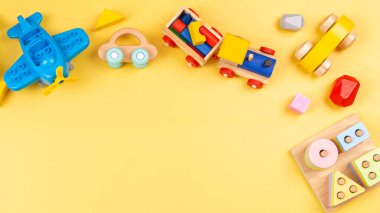 Bebek çocuklar çocuklar için oyuncak. Eğitici ahşap ve sarı arka planda plastik oyuncaklar. Üst manzara, düz uzanma