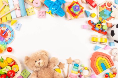 Bebek oyuncakları beyaz arka planda çerçevelenmiş. Oyuncak ayı ve bir sürü renkli eğitici tahta, plastik oyuncaklar. Üst görünüm, düz görünüm, metin için alanı kopyala