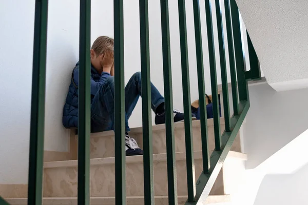Szomorú fiú ül a lépcsőn, eltakarja az arcát. Negatív érzelem, depresszió, stressz, iskolai zaklatás koncepció — Stock Fotó