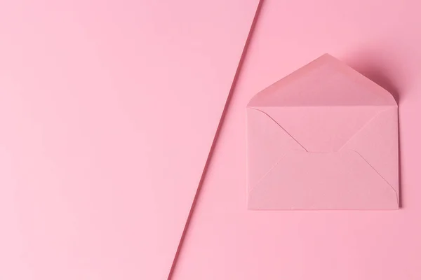 Jedna prázdná růžová obálka na pastelově růžovém geometrickém pozadí. Horní pohled, kopírovací prostor pro text — Stock fotografie