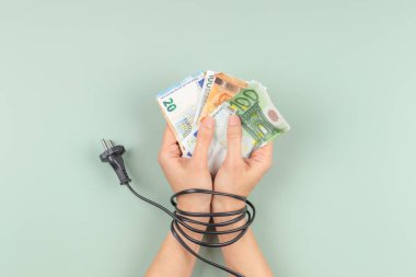 Kadın elleri elektrik kablosuyla bağlanmış. Enerji verimliliği, enerji tüketimi, artan elektrik fiyatı ve pahalı enerji kavramı