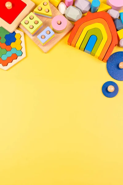 Marco de juguete para niños bebé. Juguetes educativos de madera para niños sobre fondo amarillo. Vista superior, plano — Foto de Stock