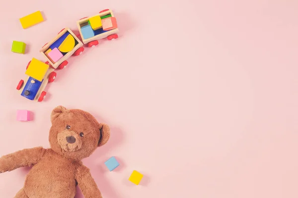 Oyuncak bebek oyuncak çerçevesi oyuncak ayı, oyuncak tren, renkli ahşap tuğlalar ve pastel pembe arka plan. Üst manzara, düz uzanma — Stok fotoğraf