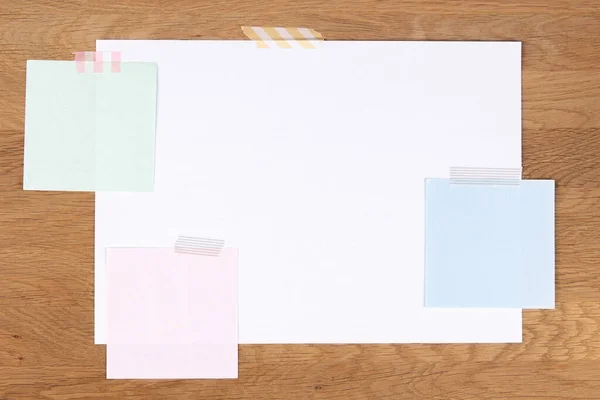 Пустая белая бумажная страница и цветные ноты, прикрепленные клейкой лентой на деревянном фоне — стоковое фото