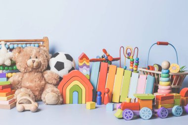 Mavi arka planda izole edilmiş çocuk oyuncakları koleksiyonu. Oyuncak ayı, tahta, plastik ve tüylü oyuncak seti. Ön görünüm
