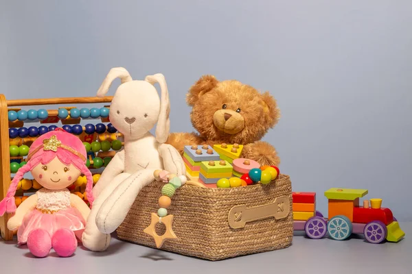 Toy box full of baby kid toys. Container with teddy bear, fluffy and educational wooden toys on light gray background. Cute toys collection for small children. Front view — 图库照片