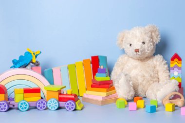 Mavi arka planda izole edilmiş çocuk oyuncakları koleksiyonu. Oyuncak ayı, tahta, plastik ve tüylü oyuncak seti. Ön görünüm