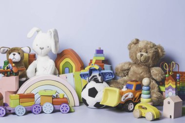 Mavi arka planda izole edilmiş çocuk oyuncakları koleksiyonu. Oyuncak ayı, tahta, plastik ve tüylü oyuncak seti. Ön görünüm