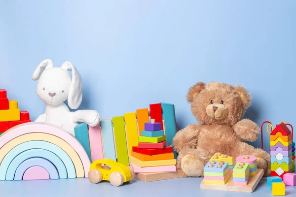 Kid toys collection isolated on blue background. Teddy bear, white bunny, wooden, plastic and fluffy educational baby toy set. Front view — 图库照片