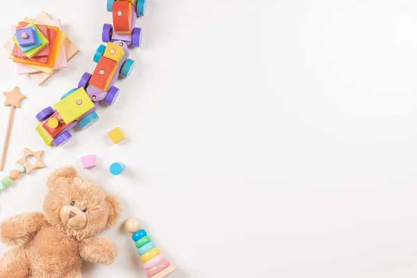 Bebek oyuncakları beyaz arka planda çerçevelenmiş. Oyuncak ayı ve renkli Montessori eğitici tahta oyuncaklar. Üst manzara, düz uzanma