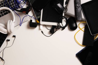 Top view to old laptop computers, digital tablets, mobile phones, many used electronic gadgets devices on white table. Planned obsolescence, electronic waste for recycling concept