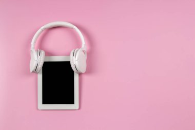 Pastel pembe arka planda kablosuz kulaklıklı dijital tablet bilgisayar. Çevrimiçi öğrenme, uzaktan eğitim, e-öğrenme, teknoloji kavramı