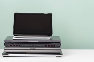 Kullanılmış dizüstü bilgisayar ve dijital tablet yığını beyaz masaya geri dönüşüm için. Yeniden kullanım ve geri dönüşüm konsepti için planlanmış eskitme, e-atık, elektronik atık