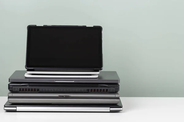 Stos starych używanych laptopów i tabletów cyfrowych do recyklingu na białym stole. Planowana przestarzałość, e-odpady, koncepcja odpadów elektronicznych przeznaczonych do ponownego użycia i recyklingu — Zdjęcie stockowe
