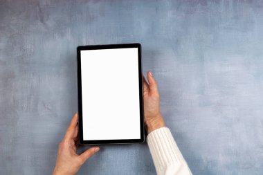 Dijital tablet bilgisayarı tutan kadın eller, beyaz ekranlı e-kitap gri arkaplandaki gibi. Üst görünüm, alanı kopyala