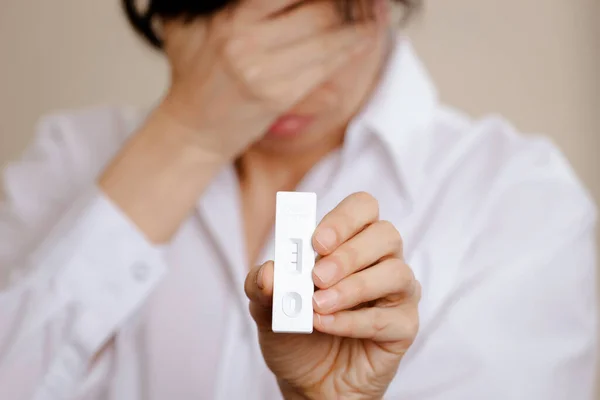 Mujer decepcionada preocupada que muestra el dispositivo de prueba de diagnóstico de antígeno rápido Covid-19 con resultado positivo en la tira de prueba — Foto de Stock