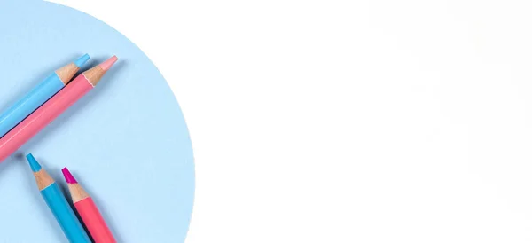 Lápices de color azul claro y rosa sobre fondo de mesa geométrico redondo azul y blanco. Vista superior. Volver a la escuela, educación, aprendizaje, arte, concepto de entretenimiento creativo — Foto de Stock
