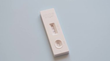 İki Covid-19 antijen hızlı test cihazı testi, mavi arka planda yan yana. Negatif işaretli bir test cihazı ve pozitif bir test sonucu. Üst görünüm