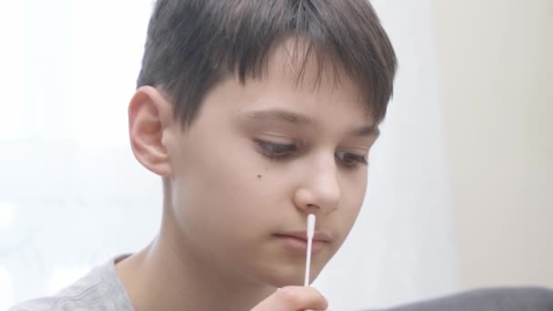 Remaja laki-laki mengambil antigen self-test untuk Covid-19 dengan cepat diagnostik tes kit. Kid menggunakan nasal swab saat melakukan tes PCR coronavirus di rumah sebelum pergi ke pelajaran sekolah — Stok Video