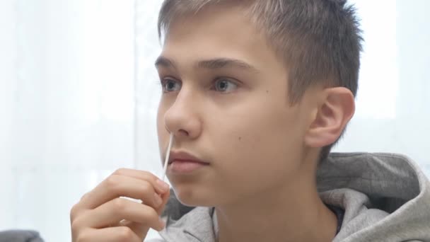 Remaja laki-laki mengambil antigen self-test untuk Covid-19 dengan cepat diagnostik tes kit. Kid menggunakan nasal swab saat melakukan tes PCR coronavirus di rumah sebelum pergi ke pelajaran sekolah — Stok Video