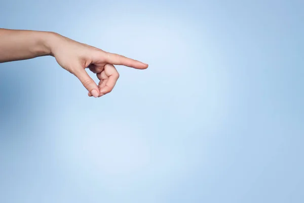 Handbewegung der Frau. Finger zeigen auf etwas auf hellblauem Hintergrund. Frontansicht, Kopierraum — Stockfoto